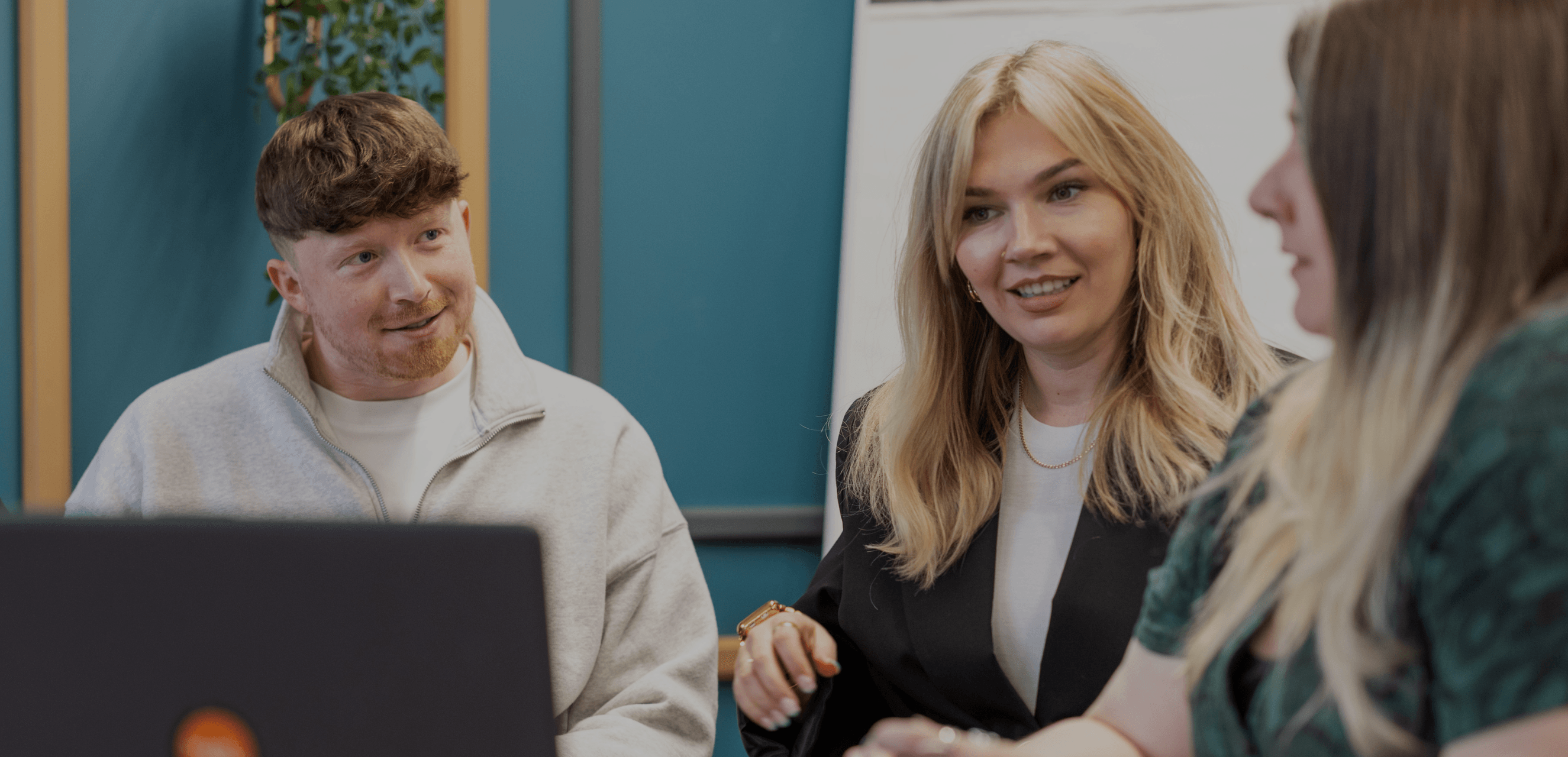 Three people sitting having a meeting in a blue office.